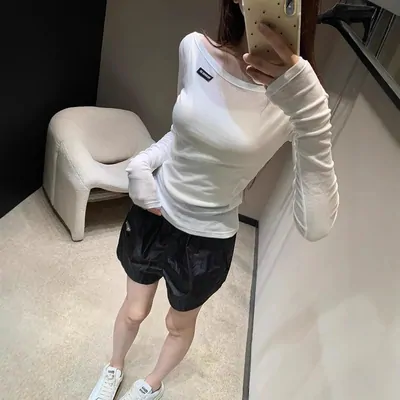 Woman wearing a white long-sleeve top and dark shorts